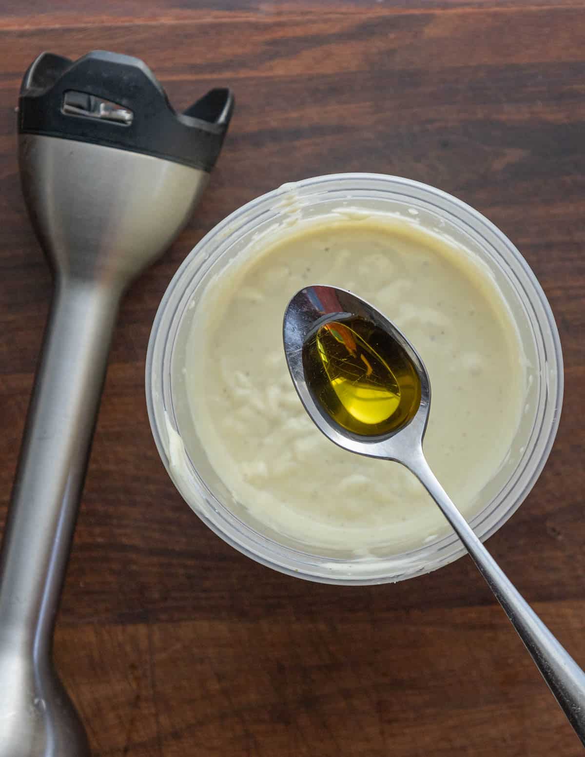 Adding a spoonful of truffle oil to finished mayonnaise to make aioli. 
