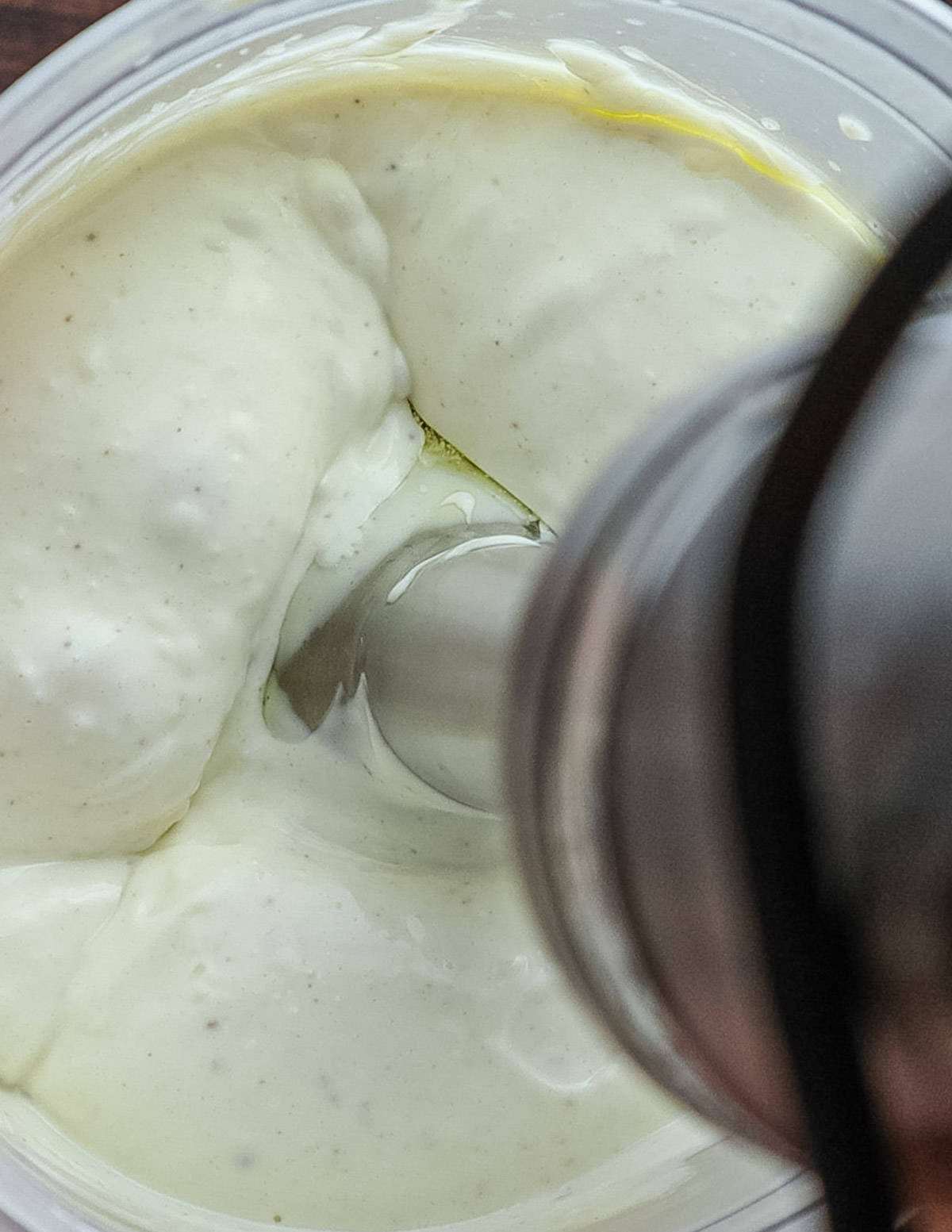 A close up image of a hand blender pureeing aioli. 
