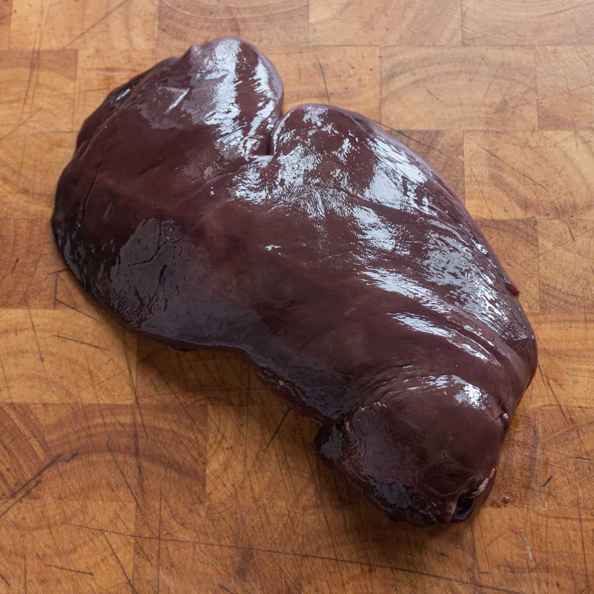 A large piece of liver on a cutting board. 