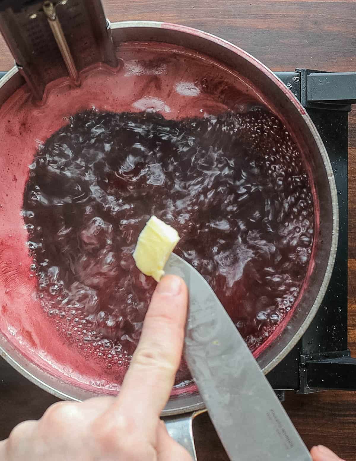 Adding a knob of butter to a pot of cooking jelly to prevent overflowing.