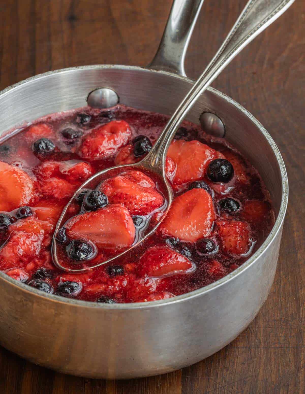 A pan of cooked strawberries and blueberries. 