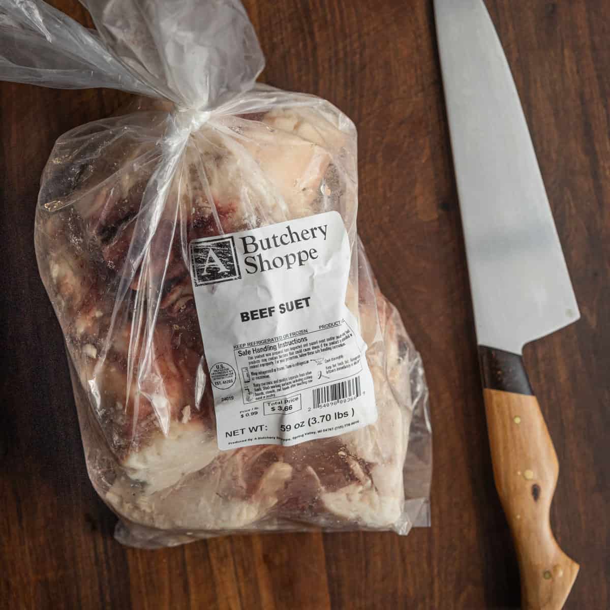 A knife next to a bag of frozen beef suet from a butcher shop. 