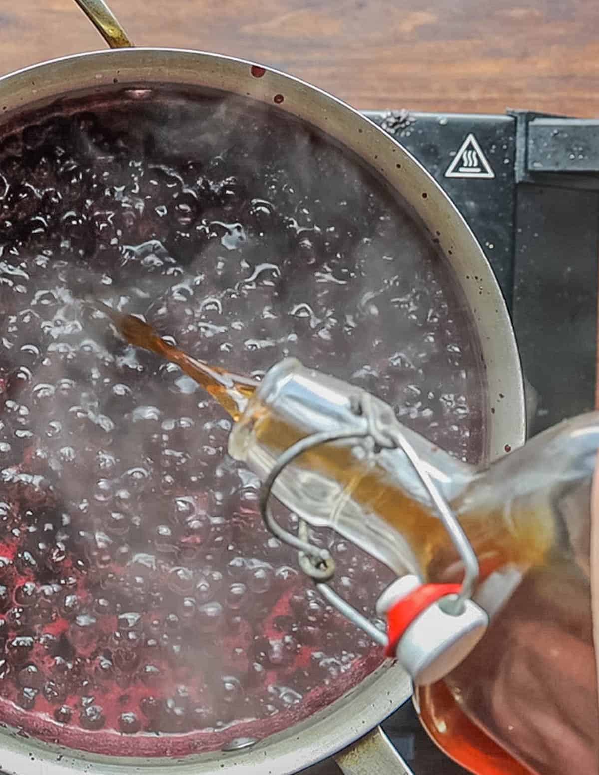 Adding a splash of vanilla extract to cooking currant preserves. 