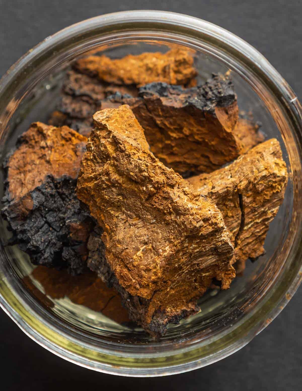 A glass jar filled with dried pieces of chaga chunks.