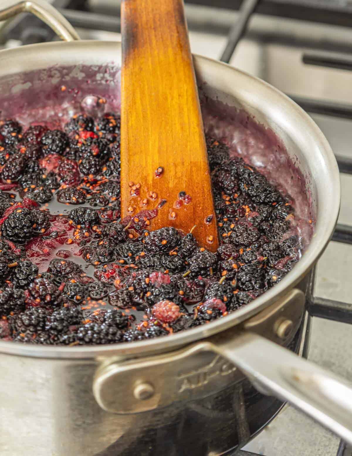 Mulberries jam cooking in a pot with a spatula. 