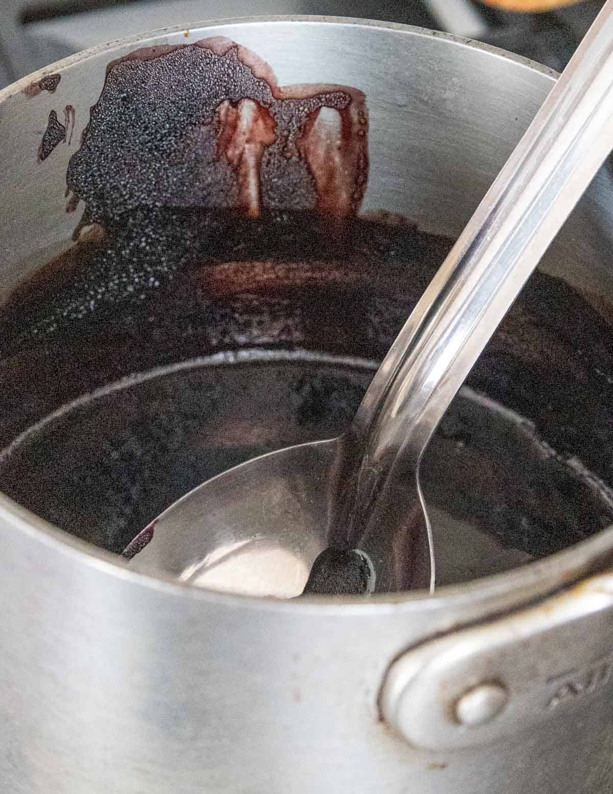 A pot with a spoon in it showing how much the mulberry juice has been reduced through cooking. 