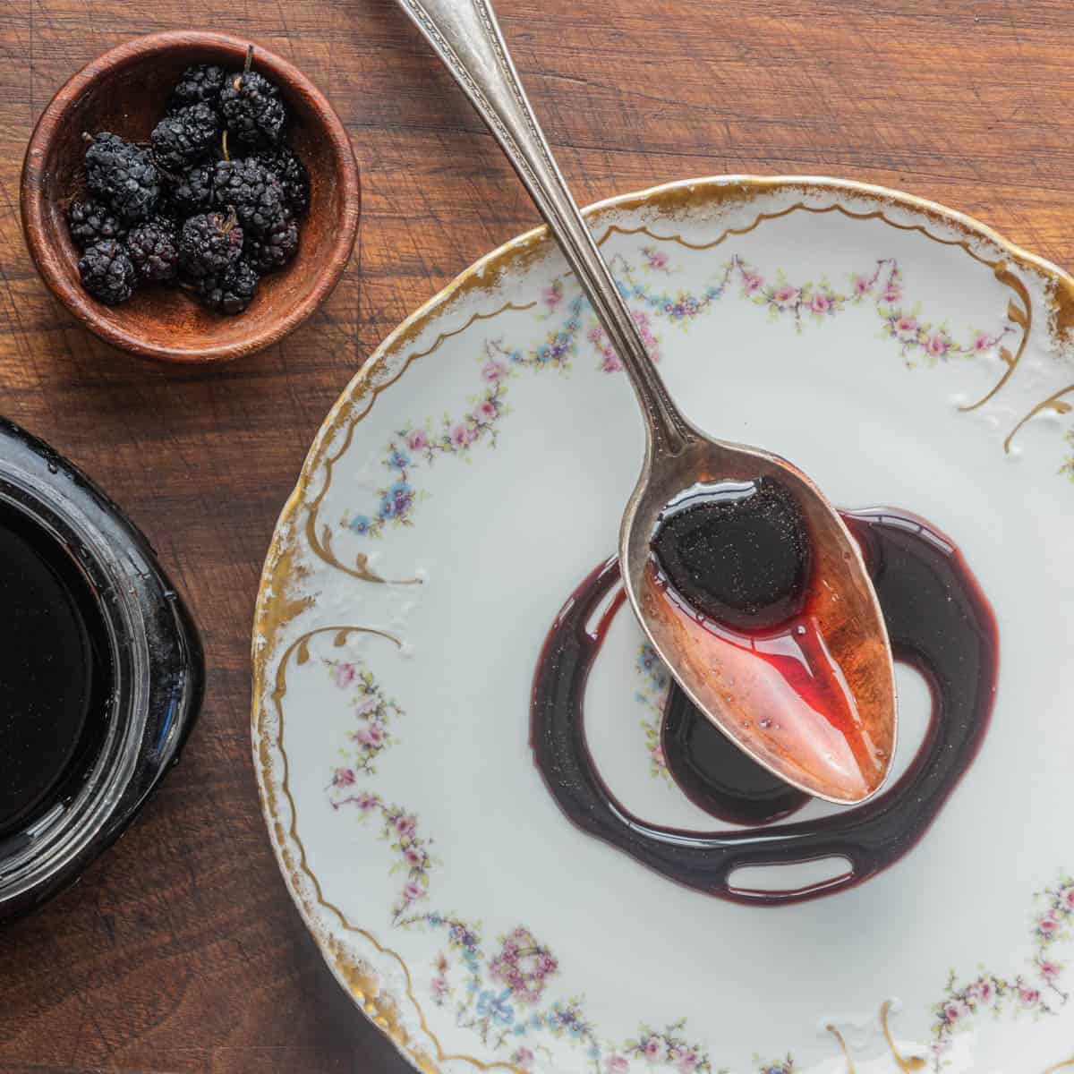 A spoonful of mulberry syrup or molasses on a china plate. 