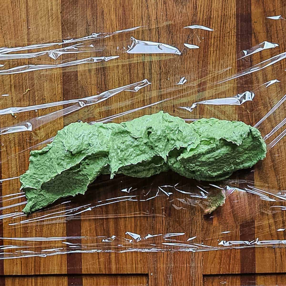 Green ramp butter being spread on cling film. 