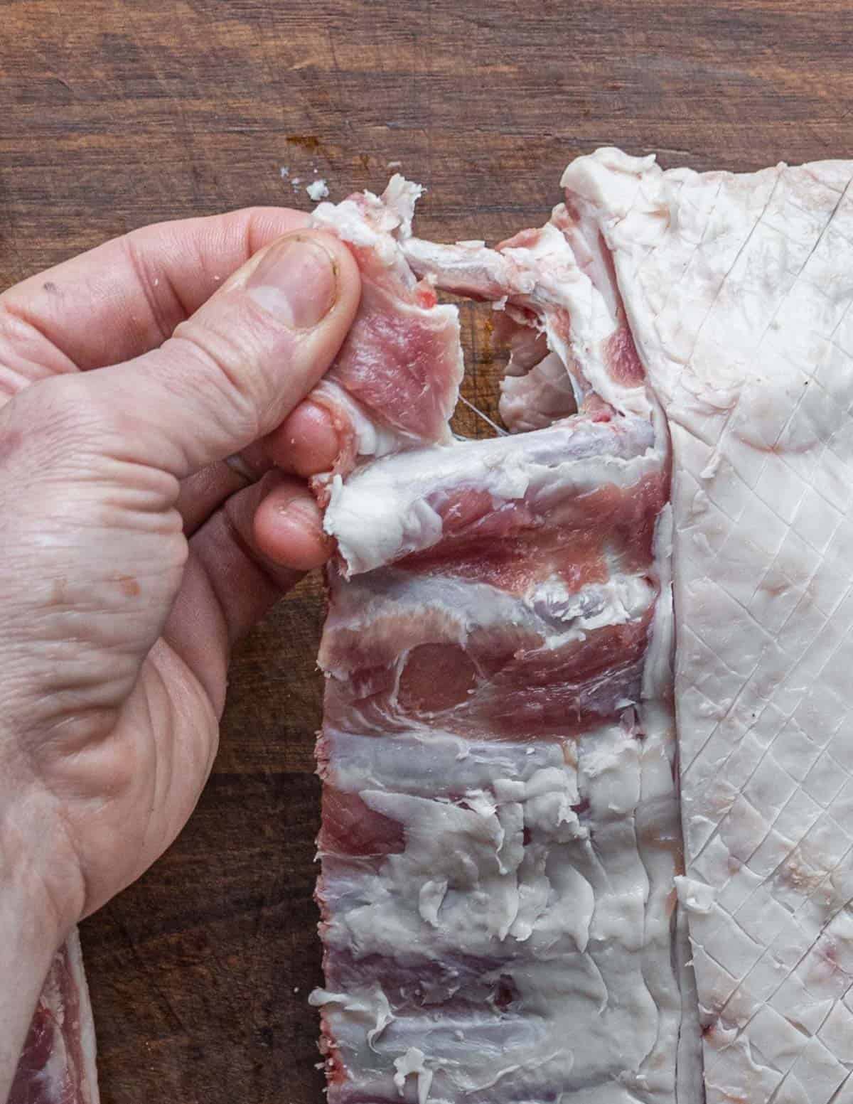 Removing meat from between the rib bones on a rack of lamb. 
