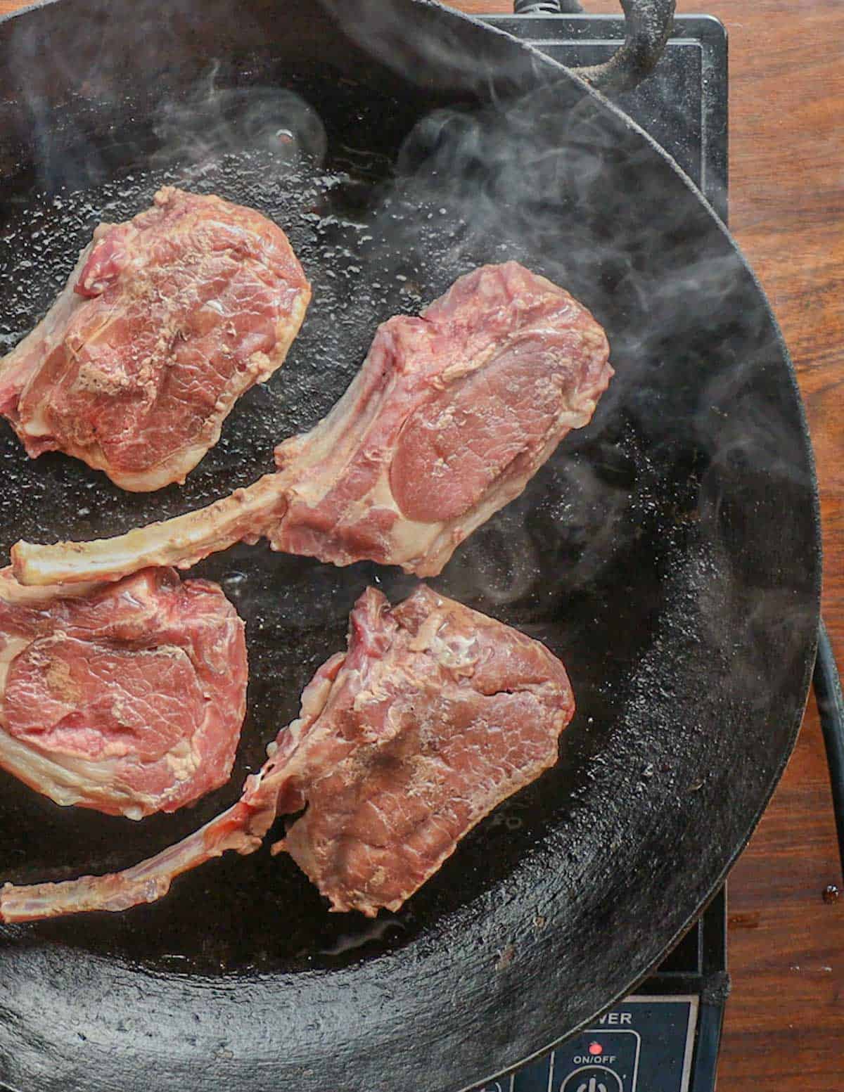 sous vide lamb chops being seared in a carbon steel pan. 