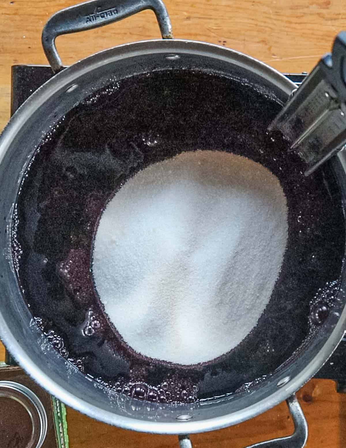 Sugar and pectin being mixed with wild grape juice to make jelly. 