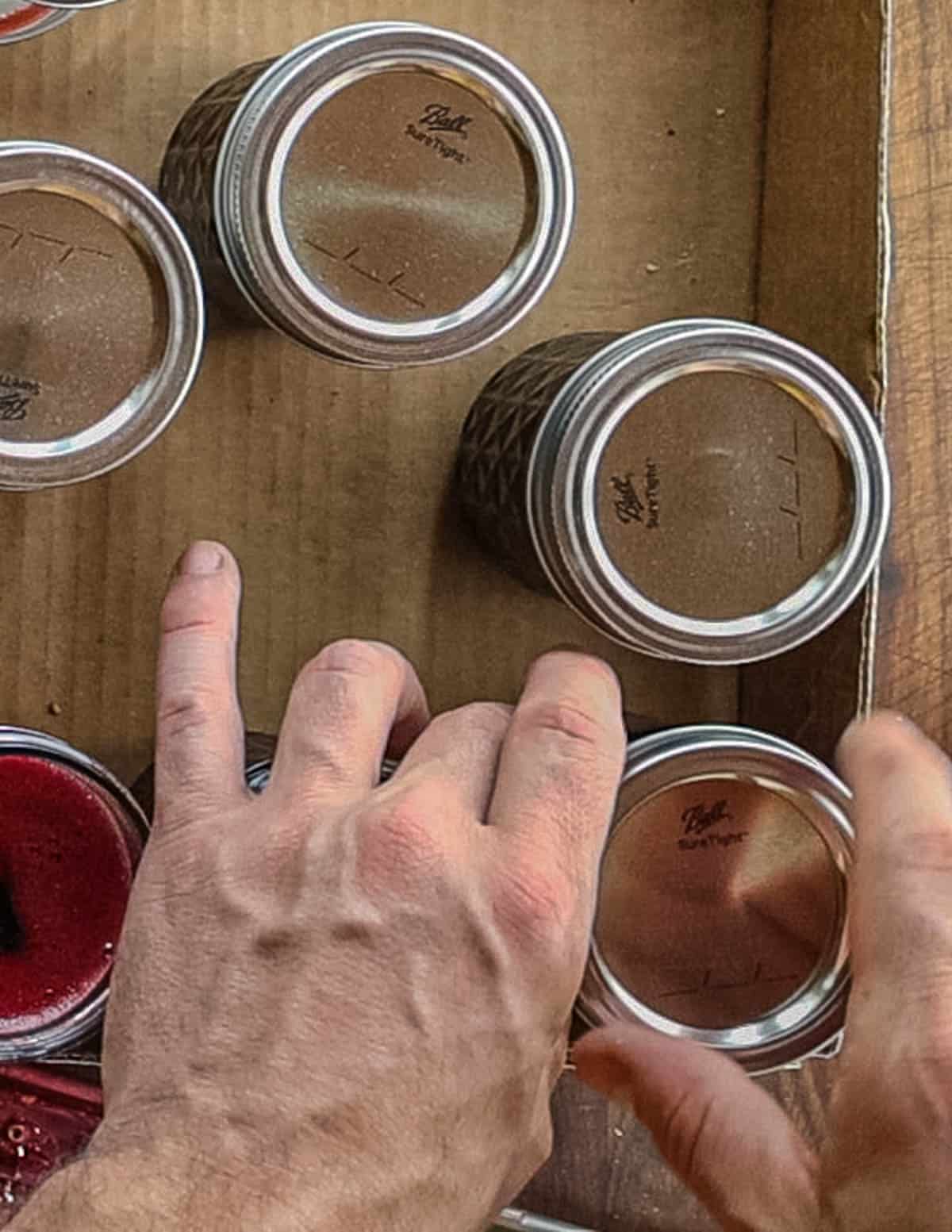 Screwing on lids to jars of grape jelly before water bath canning. 