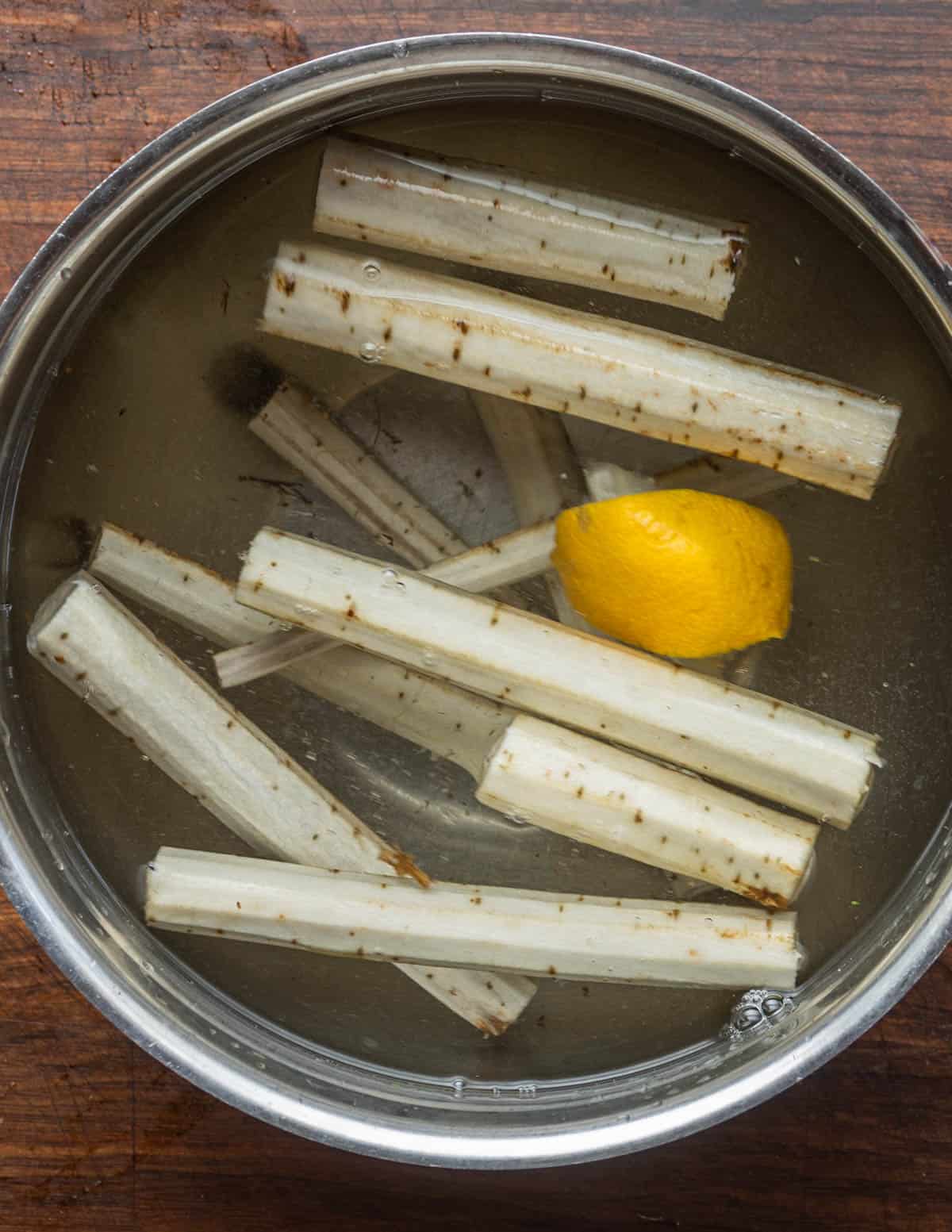Peeled burdock root being stored in a bowl of lemon water to prevent oxidization. 