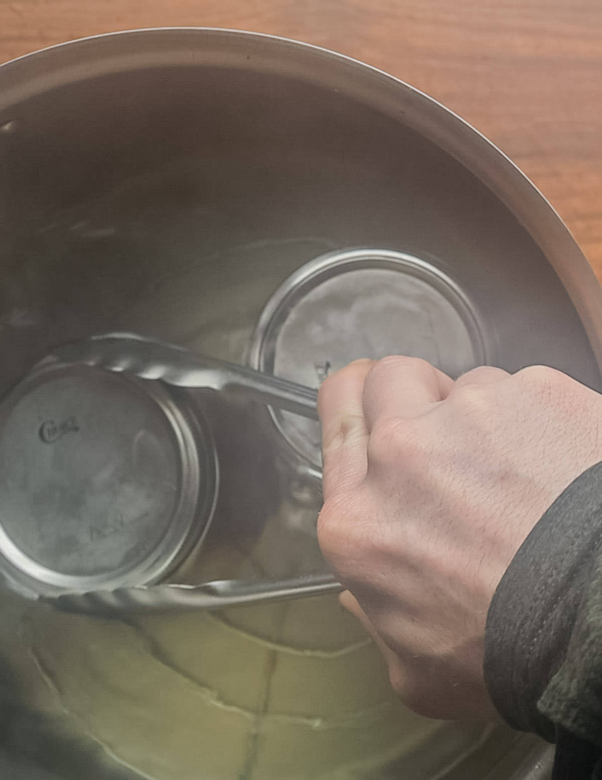 Adding jars of pickles to a water bath canner. 
