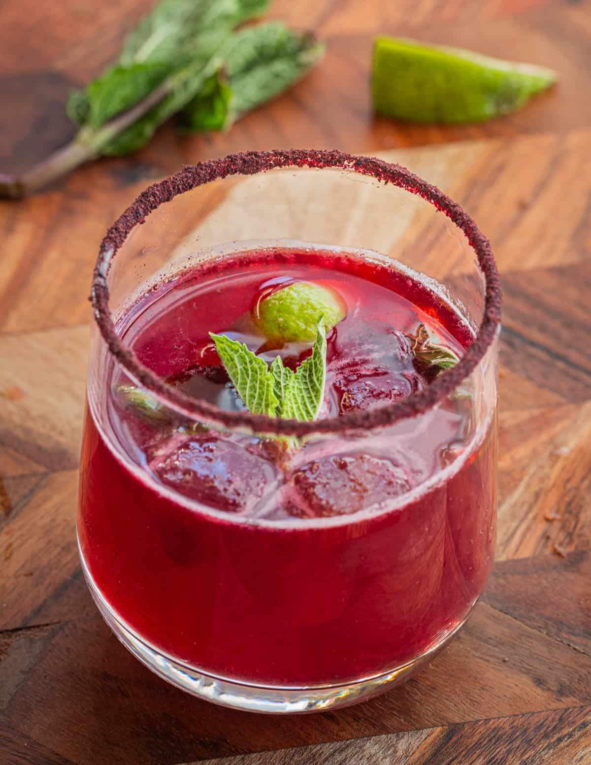 A glass of aronia agua fresca mixed with lime juice and mint. 