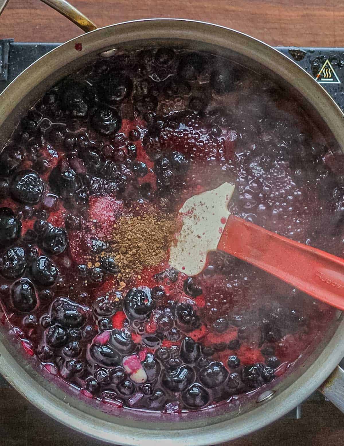 A pan of wild blueberry sauce cooking and steaming.