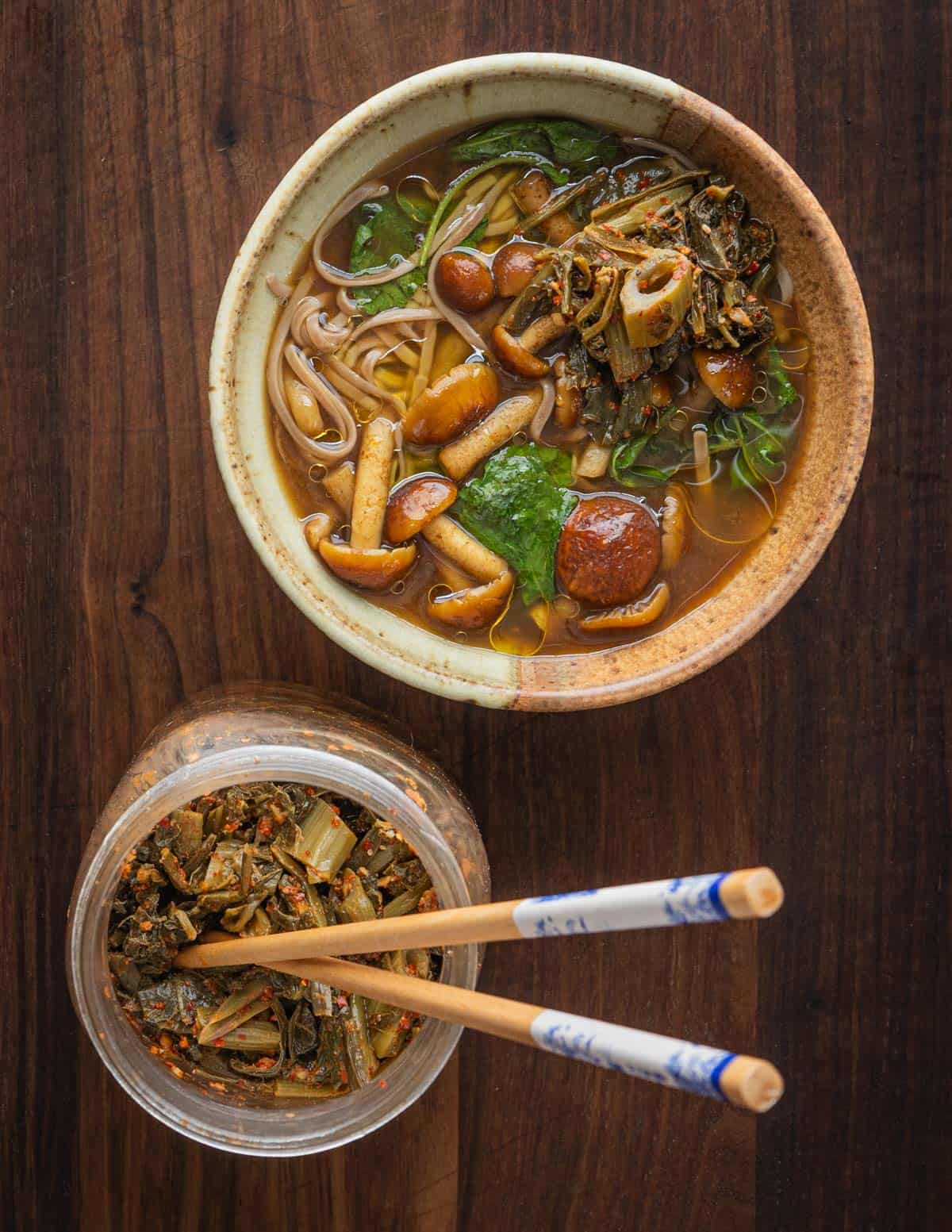 A bowl of chestnut mushroom soup garnished with fermented wild lettuce kimchi. 