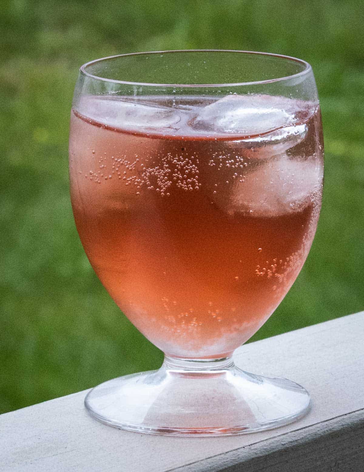 Chokecherry syrup cocktail with chokecherry pit liqueur in a glass with ice.