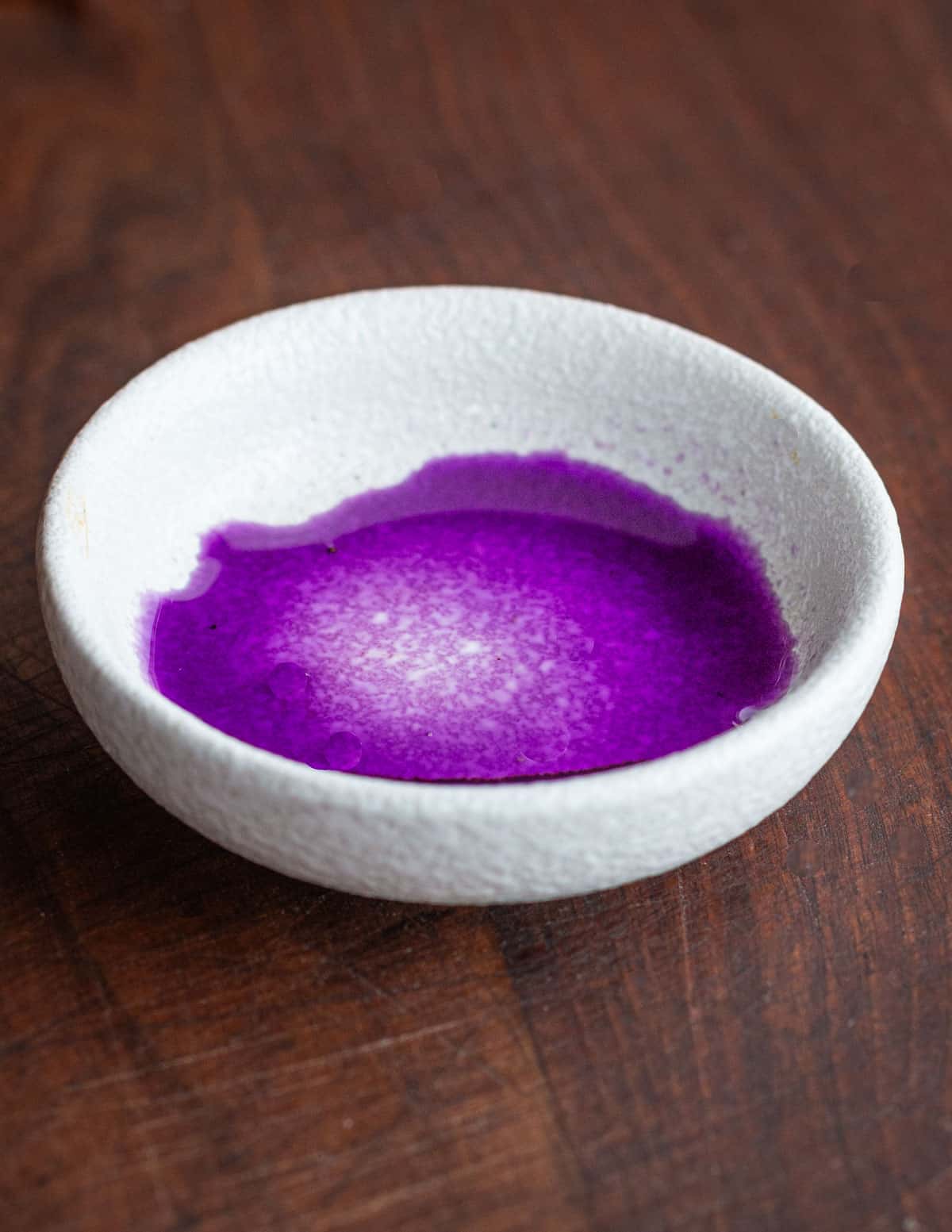 purple black nightshade berry juice in a small white bowl.