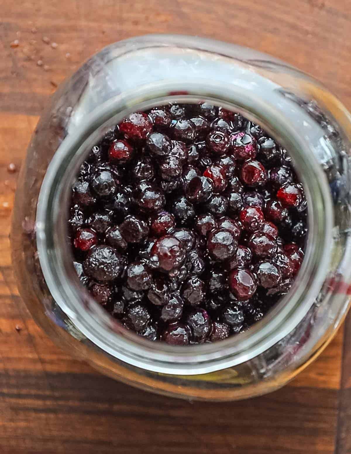 A jar filled with fresh wild blueberries. 