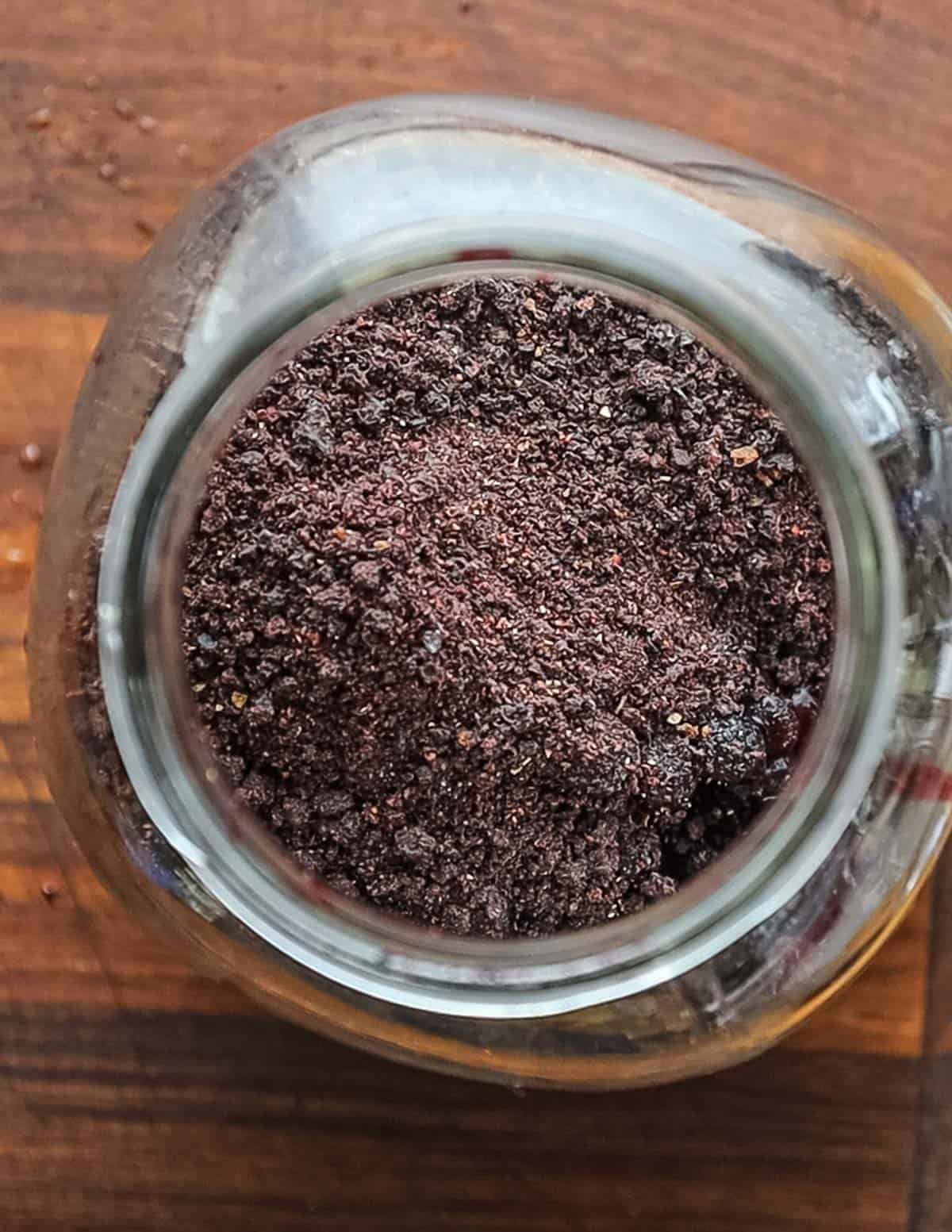 Adding ground wild blueberry powder to a mason jar. 