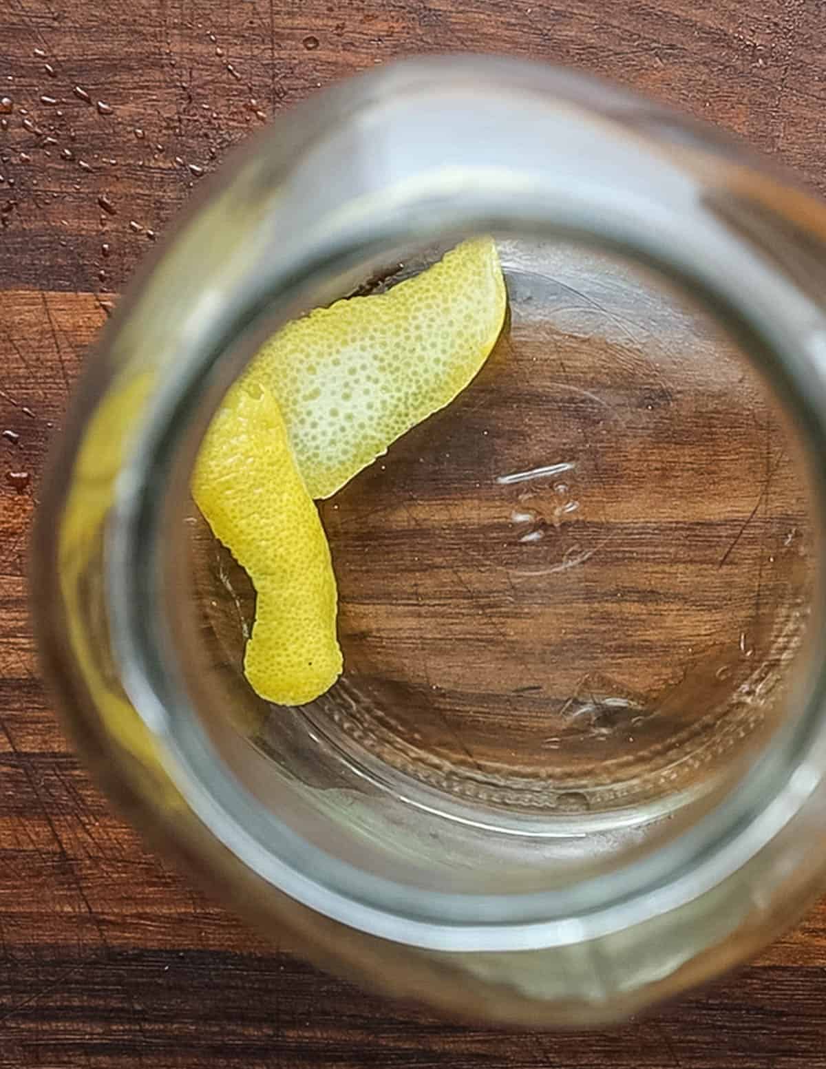 Adding a strip of lemon peel to a mason jar.