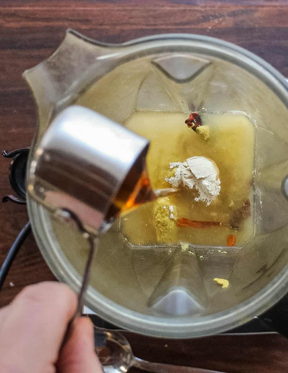 Adding maple syrup or honey to a blender. 