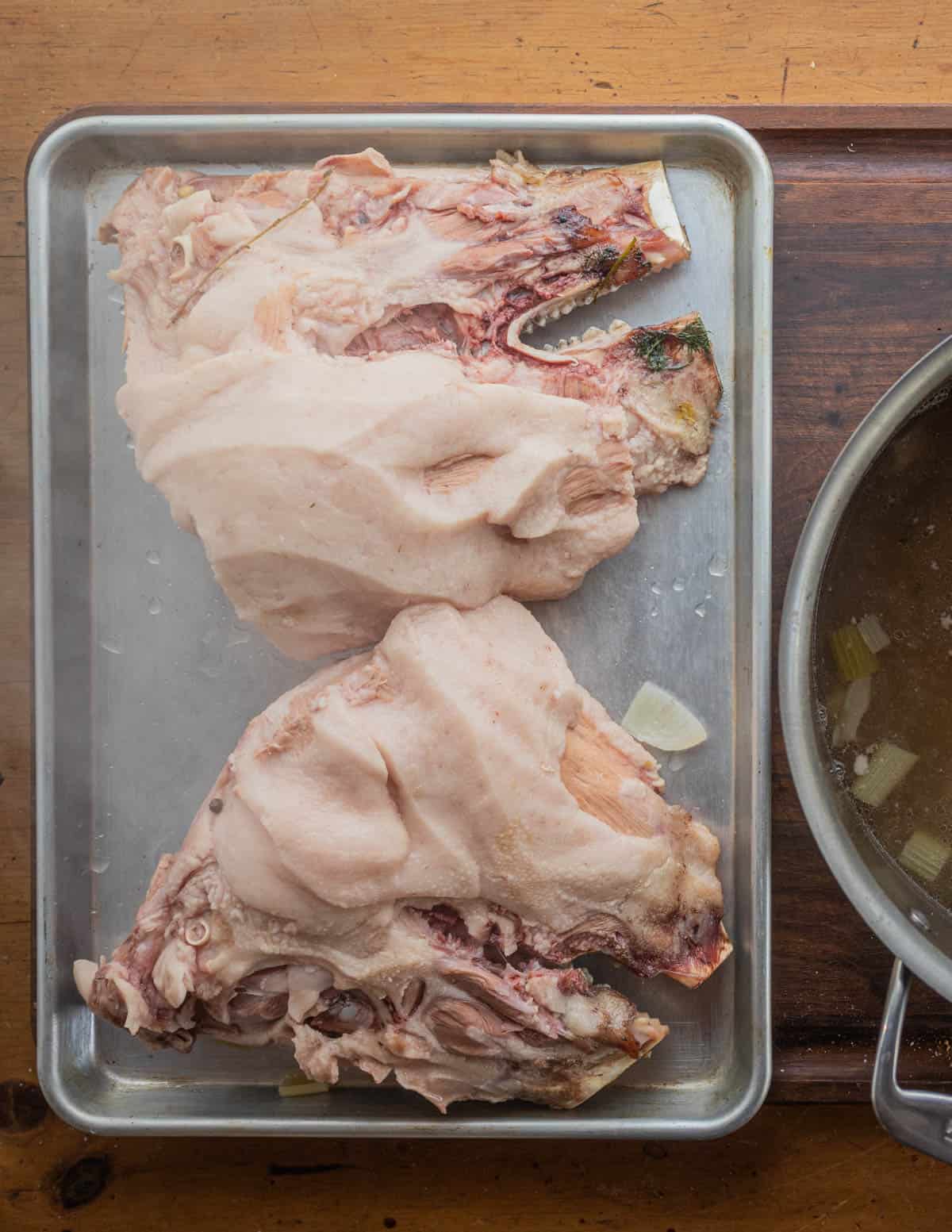 Two cooked pig head halves on a baking sheet. 