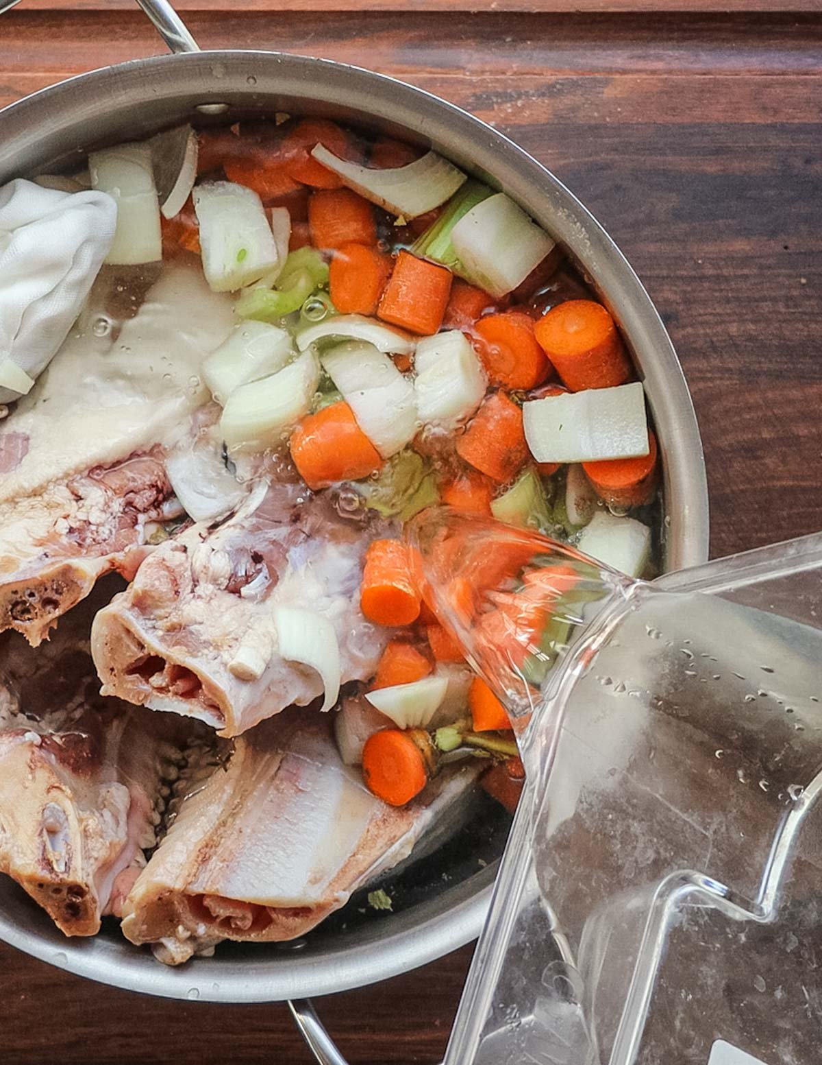 Adding water and vegetables to a pig head in a pot. 