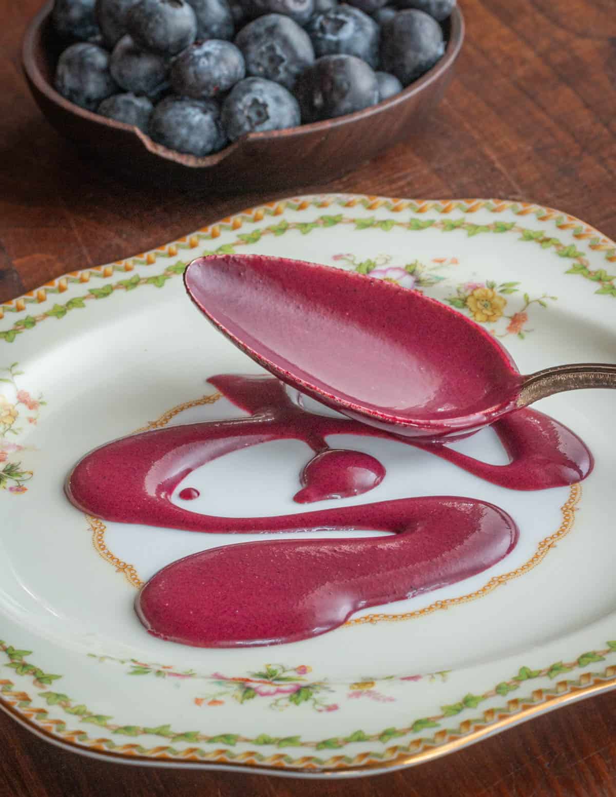A spoonful of blueberry coulis sauce on a China plante. 
