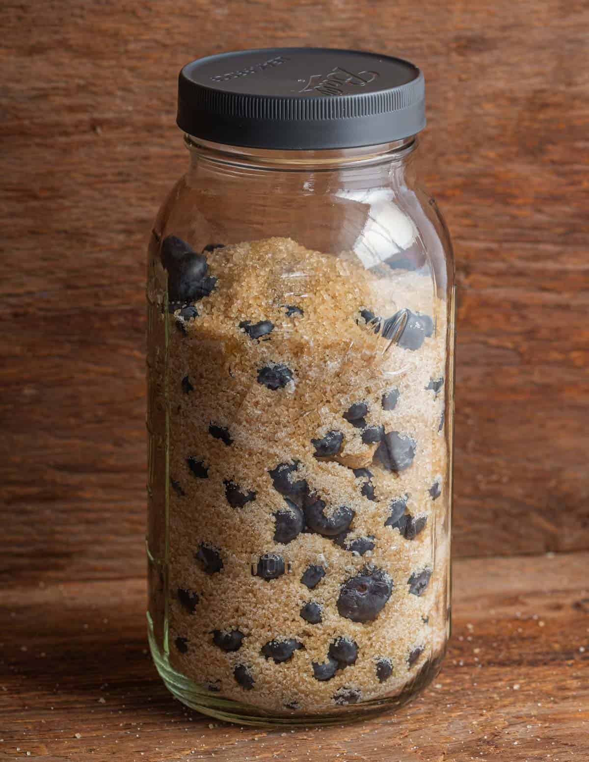 A jar of blueberries and sugar mixed together.