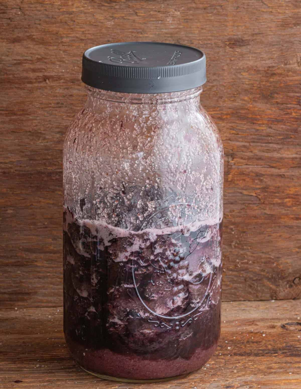 A jar of fermenting blueberries in syrup. 