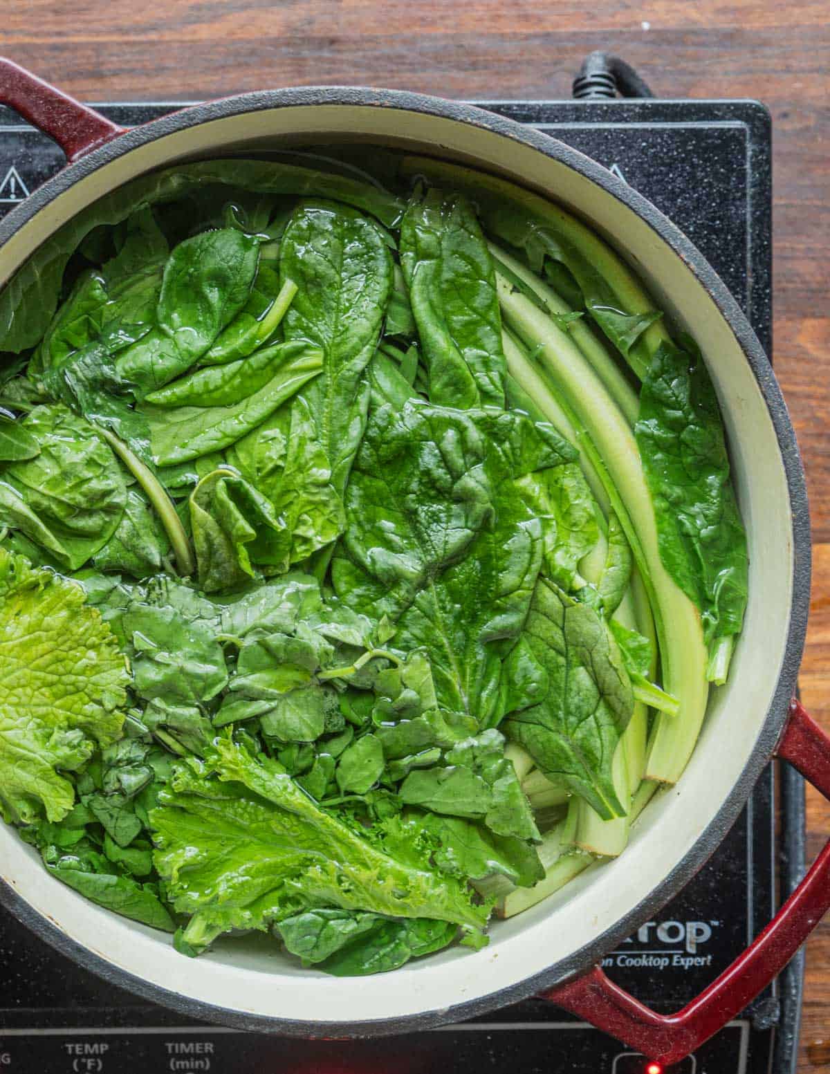 Blanching spinach and mixed greens in boiling salted water. 