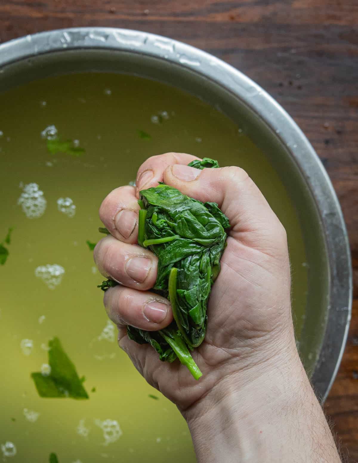 Squeezing the water from cooked spinach and leafy greens. 