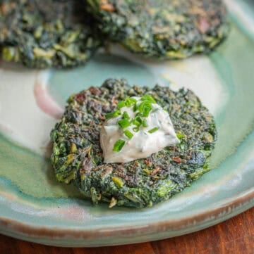 Green burgers or spinach patties served on a plate with dip garnished with chives.