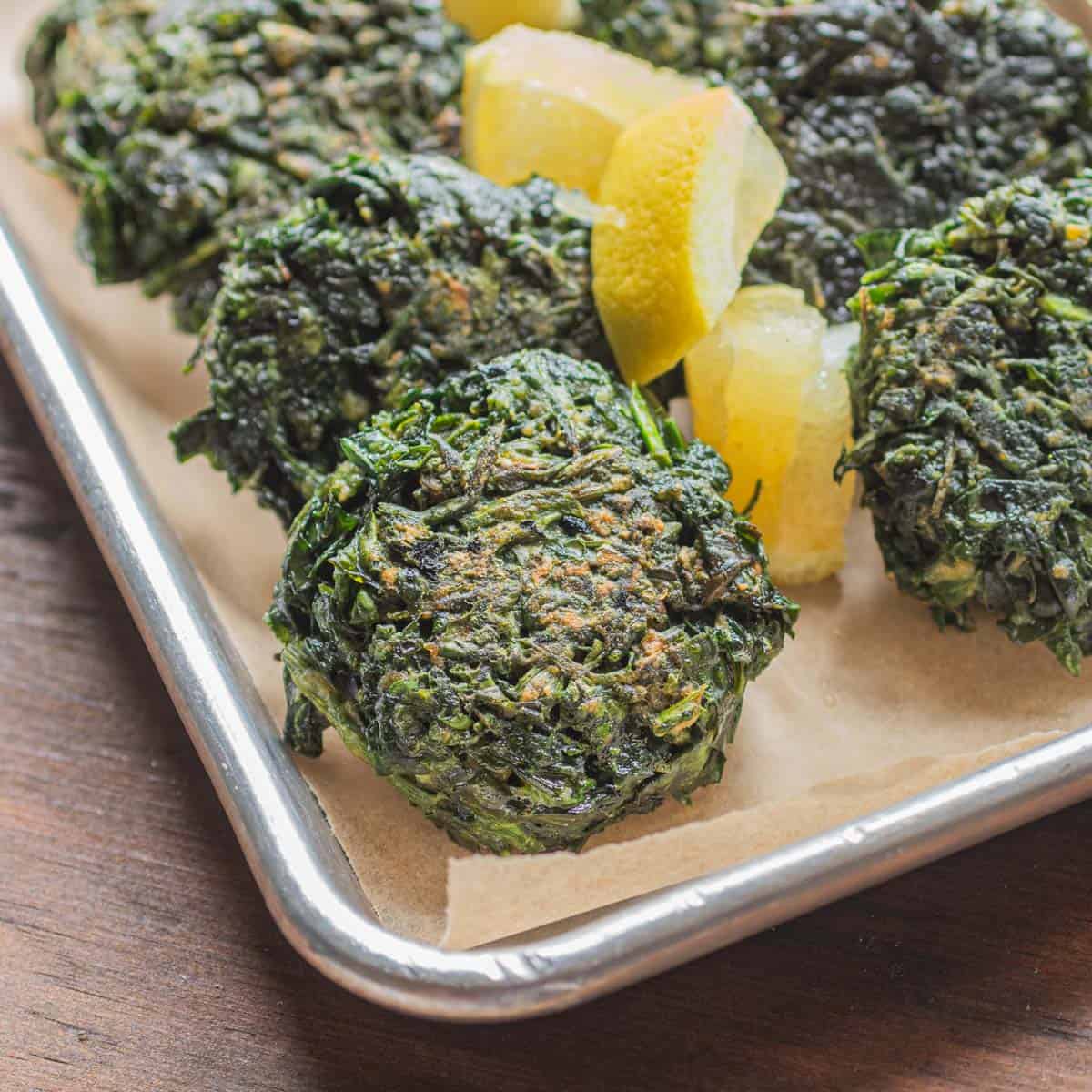 Green burgers or spinach patties served with lemon wedges. 