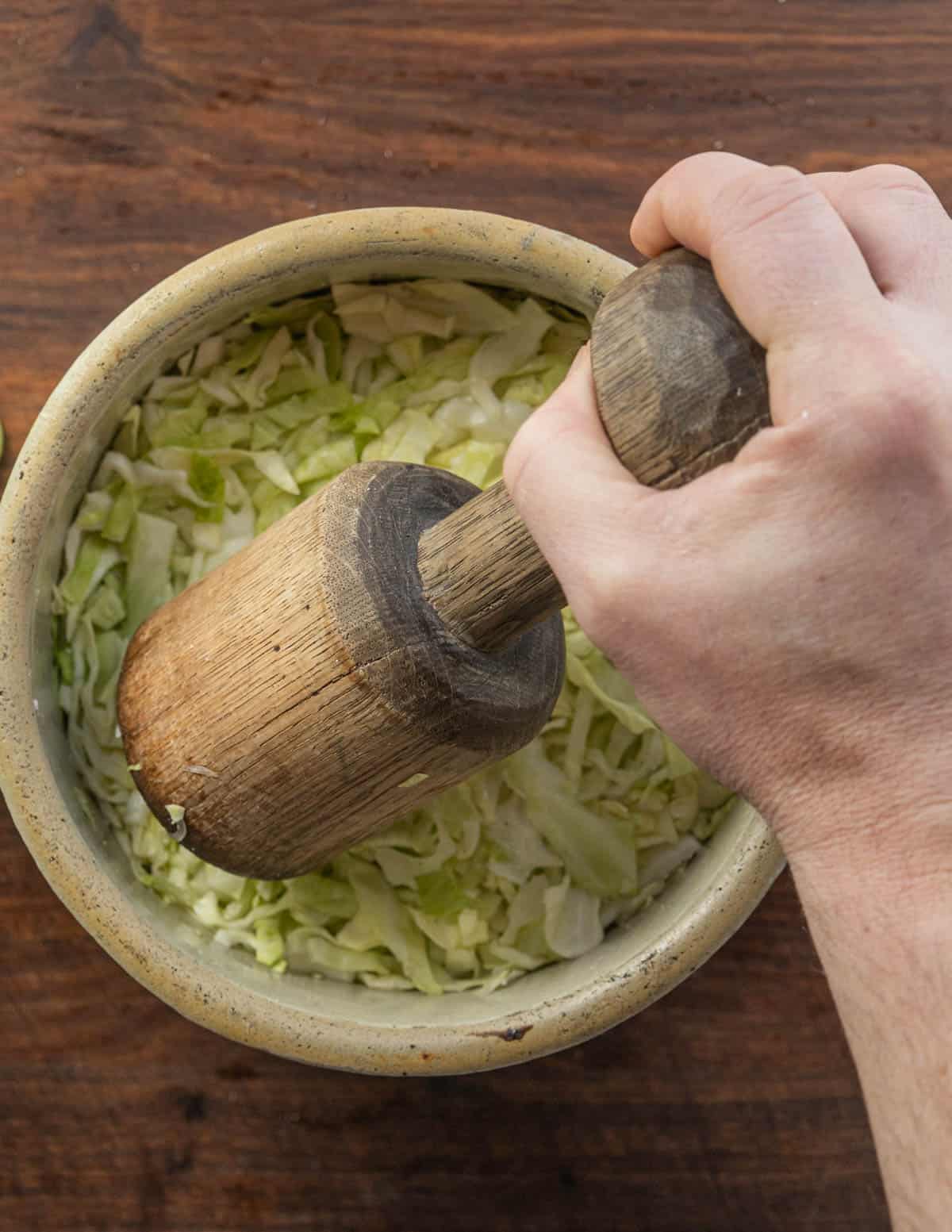 Pounding salted cabbage using a mallet. 
