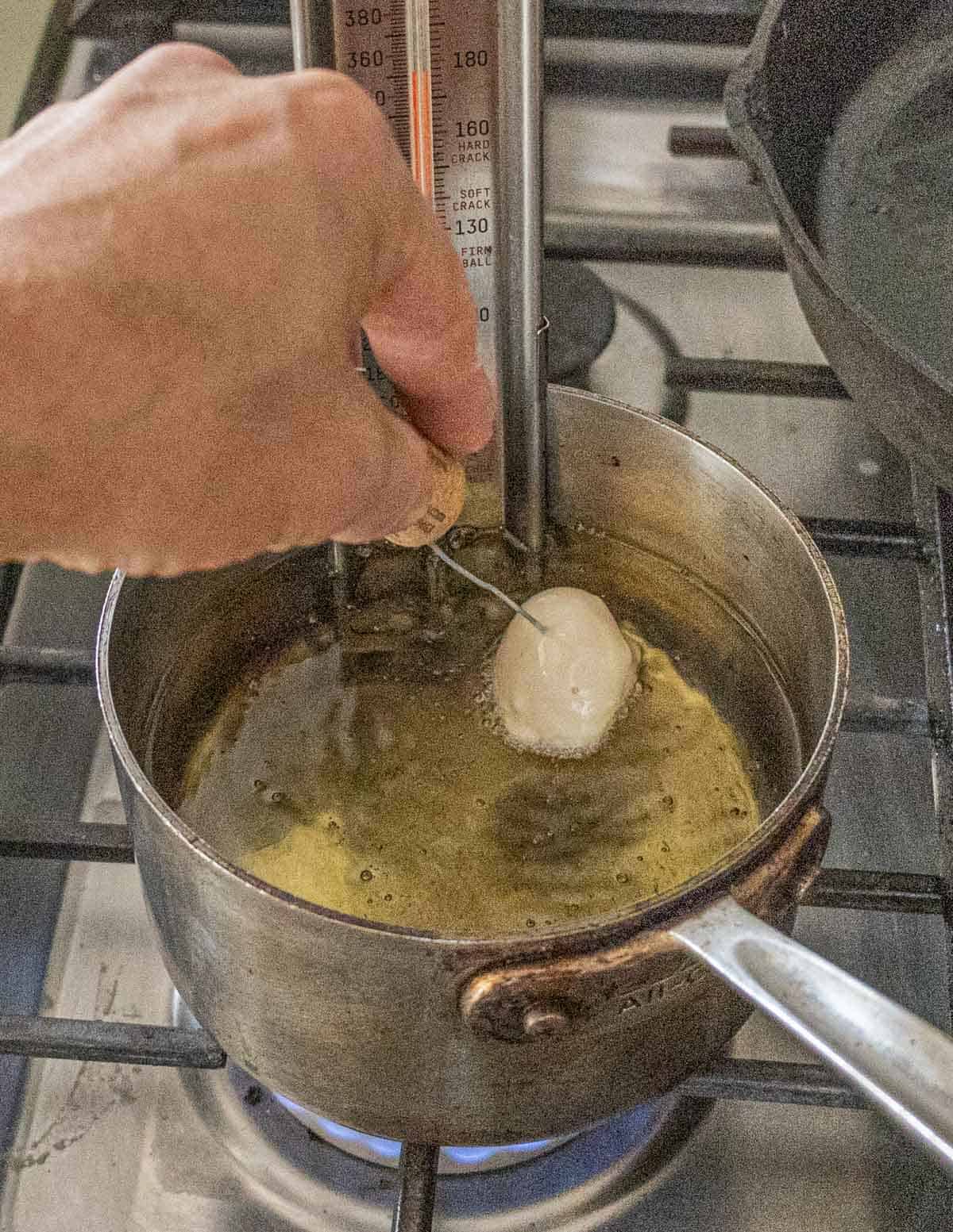 Adding tempura mushrooms to oil with a toothpick. 