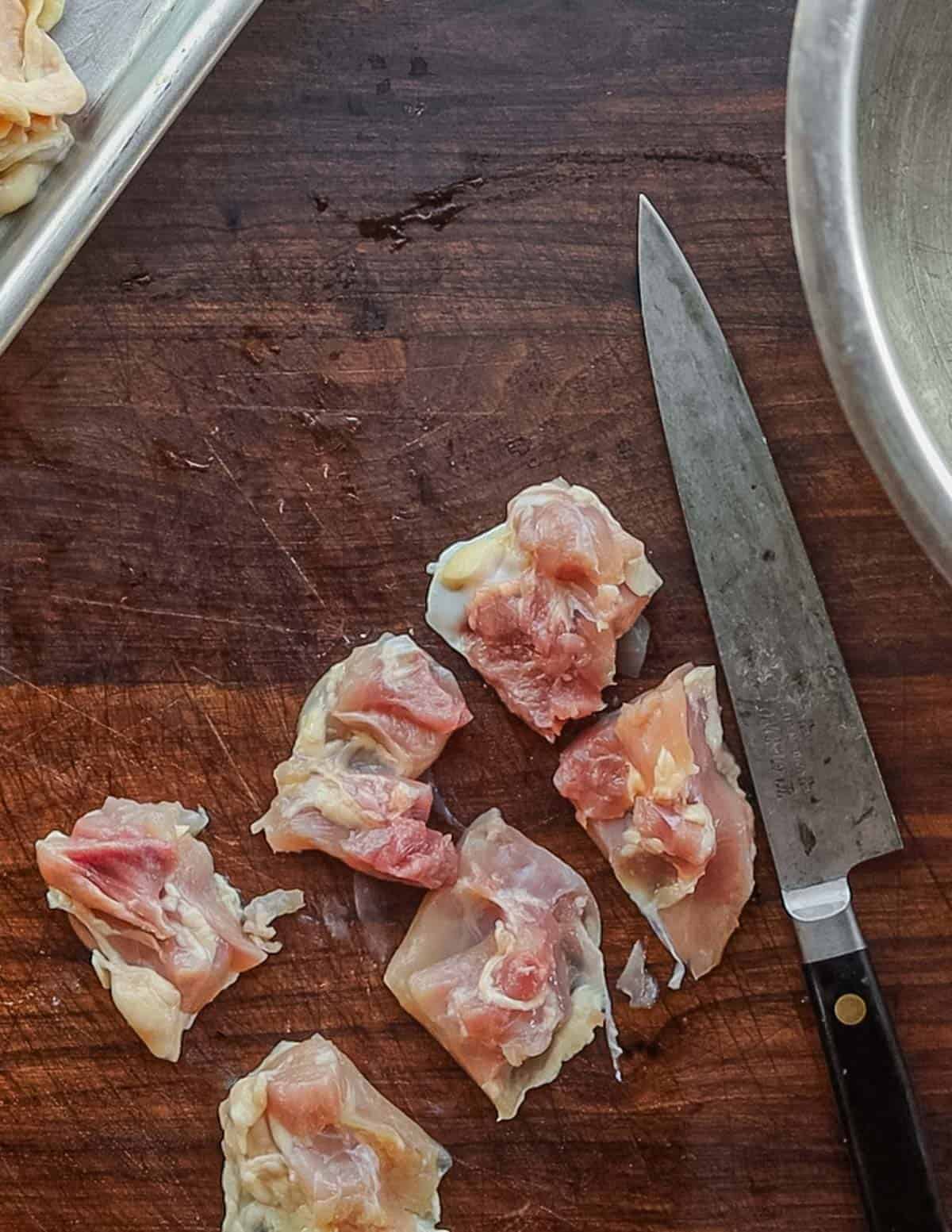 Cutting boneless chicken thighs into pieces. 