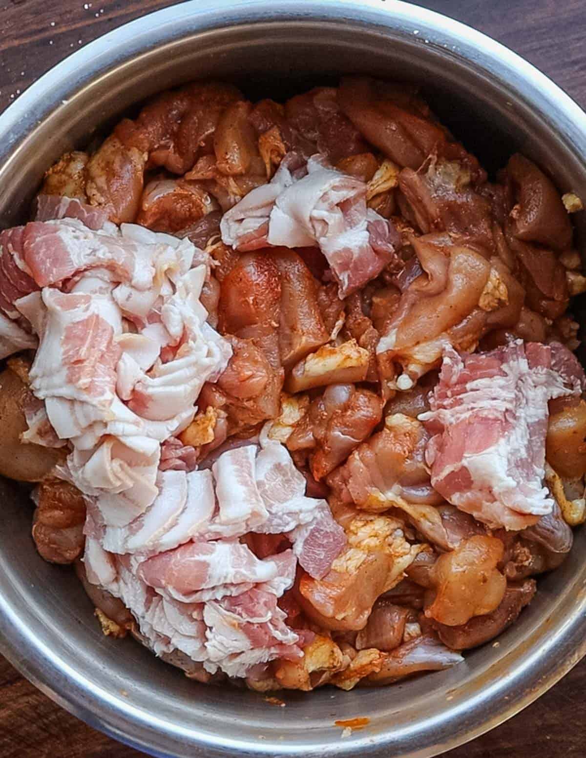 Adding diced bacon to chicken thighs. 