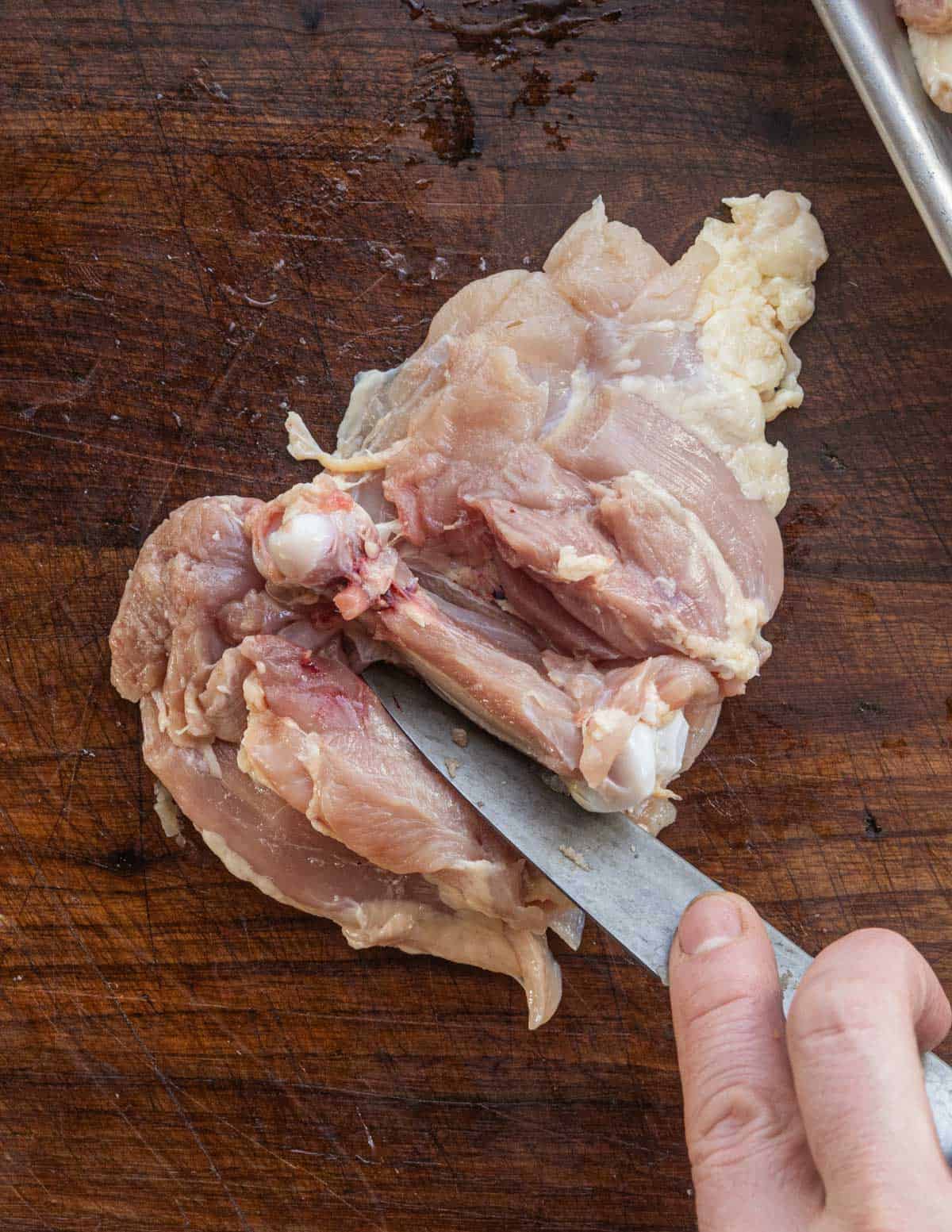 Removing the thigh bone from chicken thighs. 