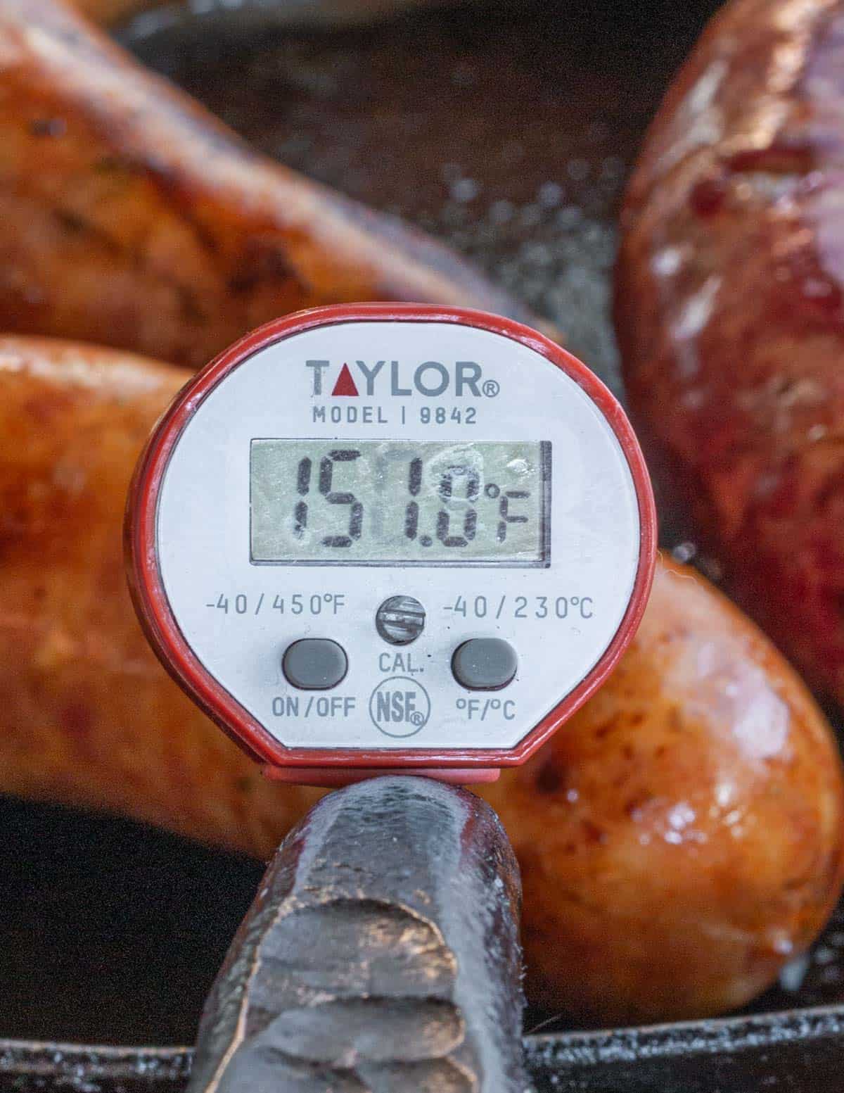 A close up picture of a thermometer reading 150 F in a smoked chicken sausage. 