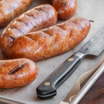 Smoked chicken andouille sausage on a tray next to a knife.
