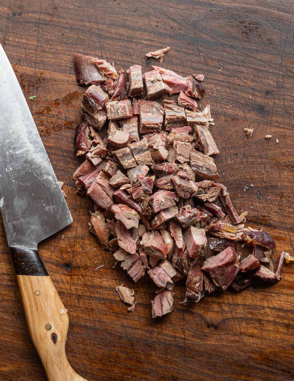 Cutting cooked smoked meat into pieces for soup.