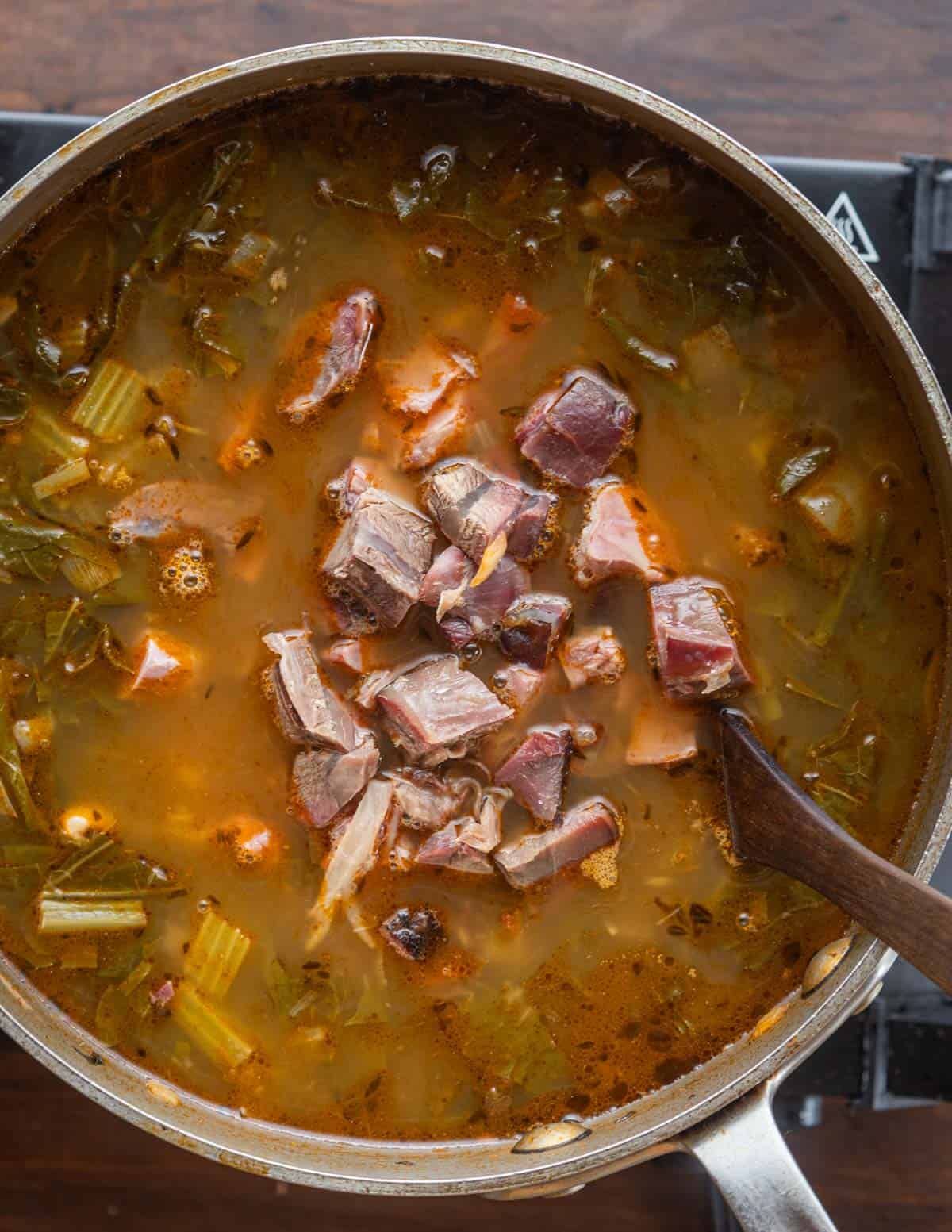 Adding cooked meat to a soup. 