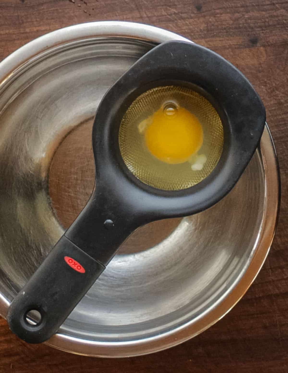 Draining an egg in a strainer before cooking.