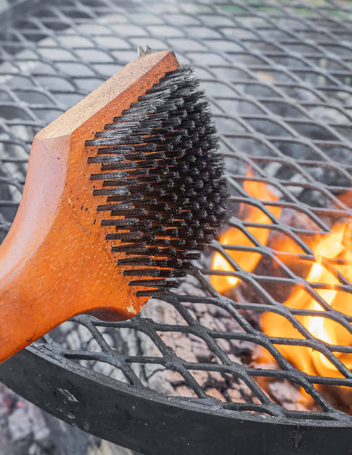 Cleaning a kudu grill wood fire grill using a grill brush.