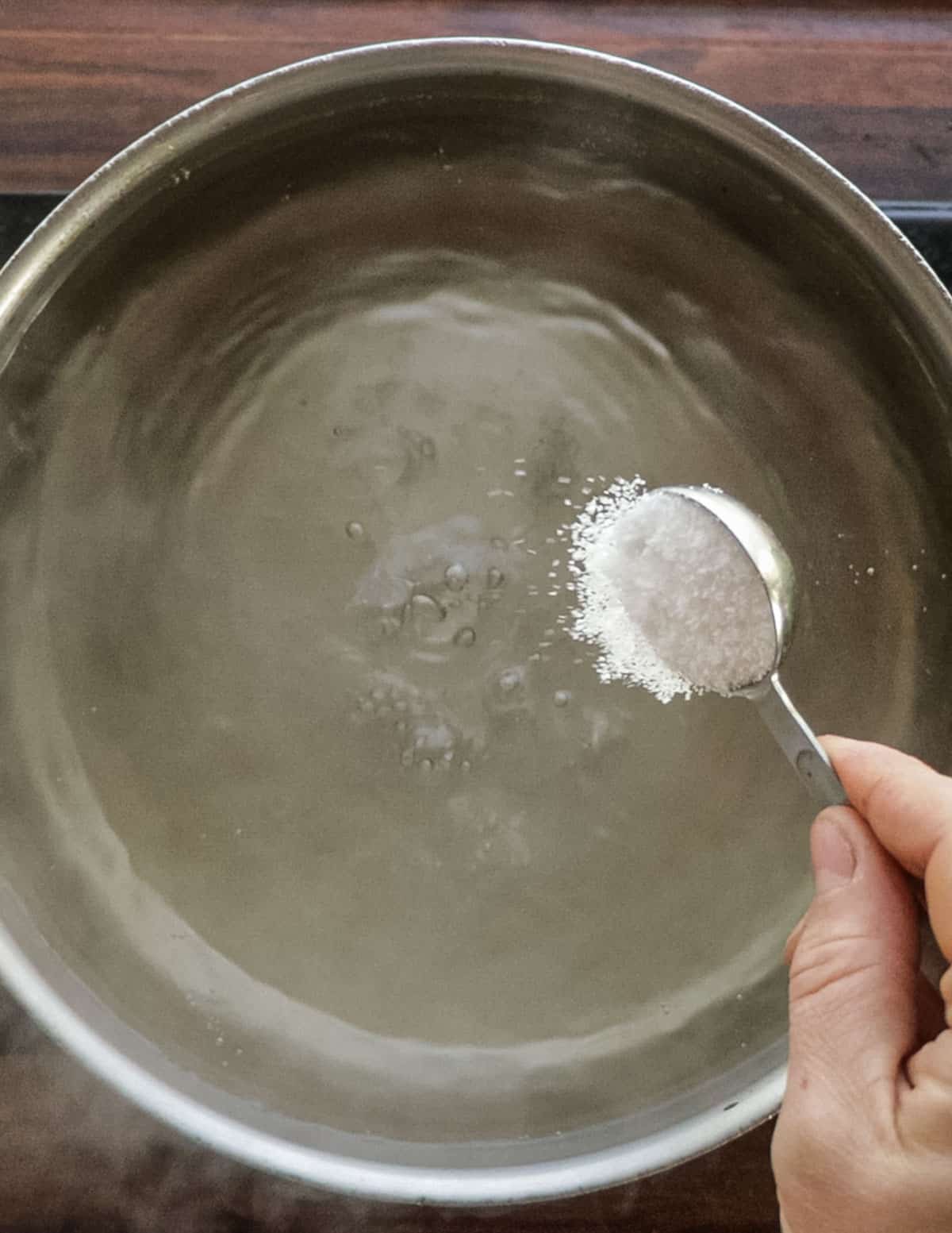 Adding salt to a pot of water. 