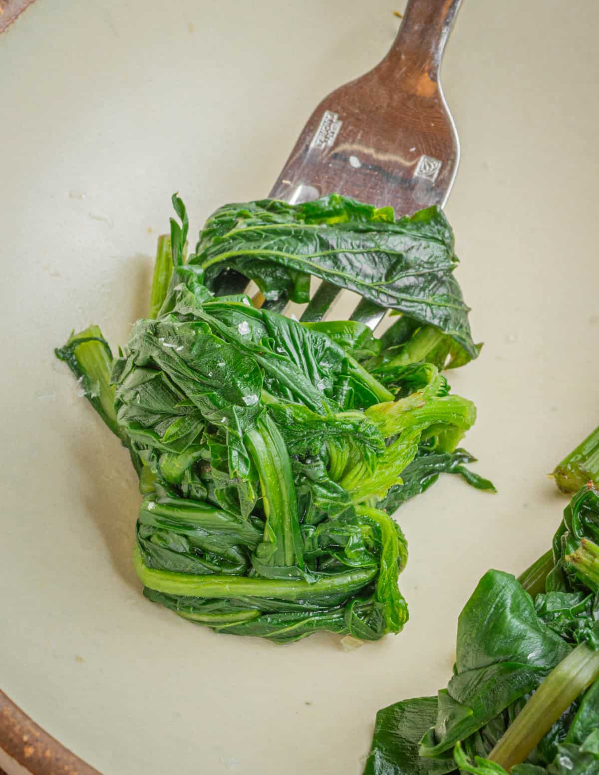 Twirling cooked horta greens around a fork to eat. 