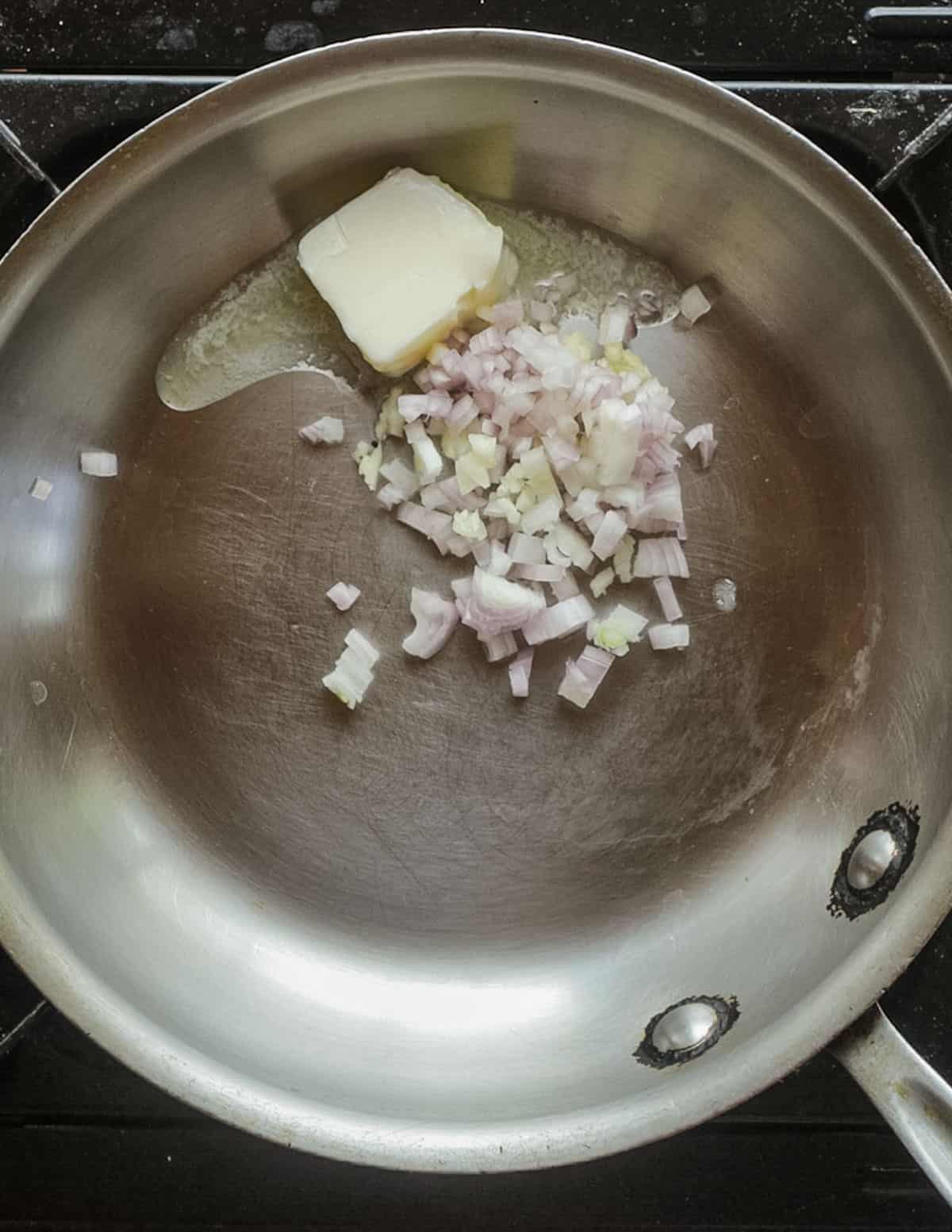 Heating butter in a pan with shallots and garlic. 